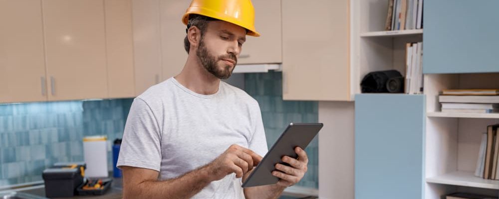 builder-helmet-working-with-tablet-kitchen-background