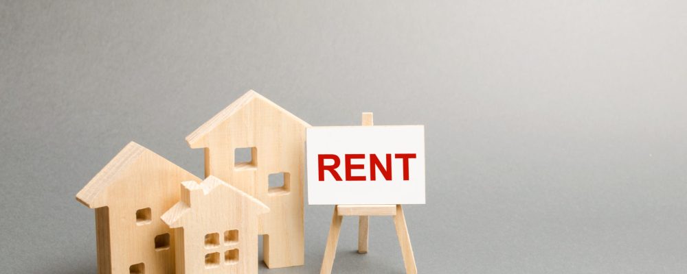 Three figures of houses and an easel with the word rent. The concept of temporary rental housing and real estate. Realtor services, search for optimal options. The choice between renting and buying.